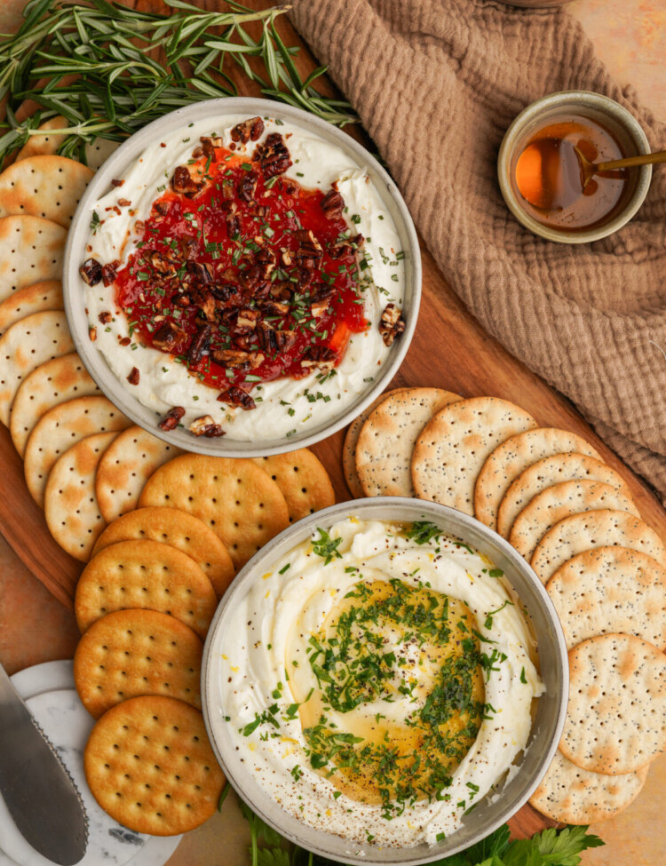 an above photo of two bowls of goat cheese dip with crackers around them on a cutting board