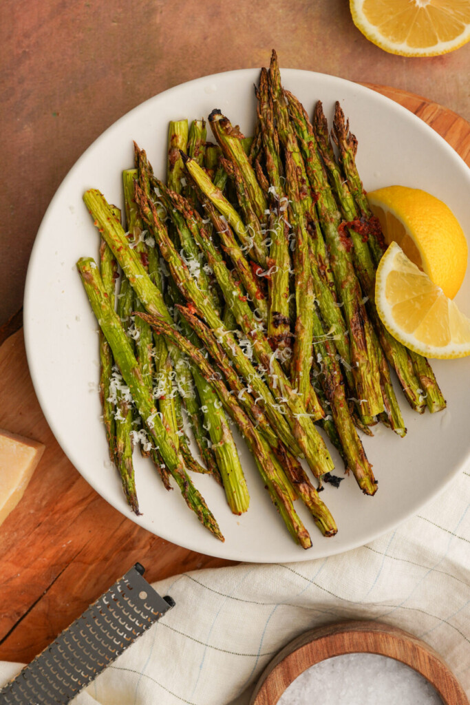 air fryer asparagus on a white plate with slices of lemon