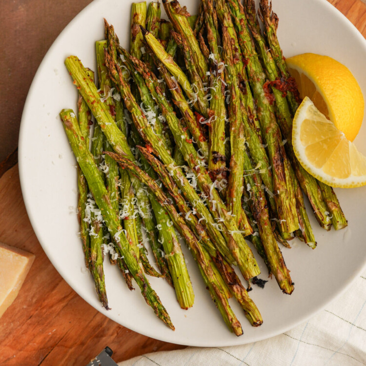 an above photo of air fryer asparagus on a white plate with slices of lemon