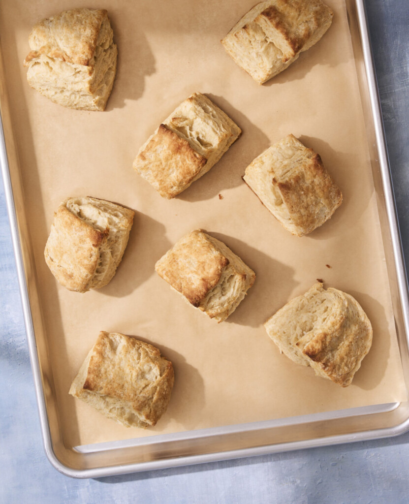 an above view photo of honey butter biscuits on a baking sheet with parchment paper