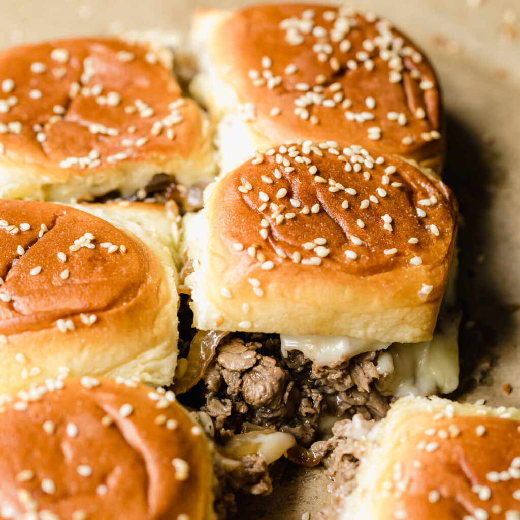 a side view photo of cheesesteak sliders on a baking tray