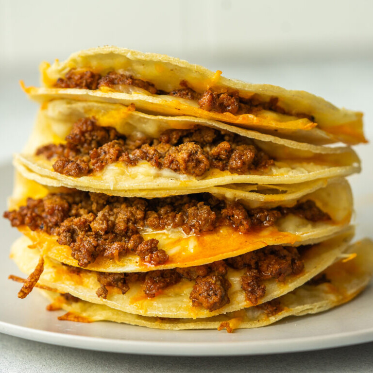 a photo of a stack of ground beef baked tacos on a white plate