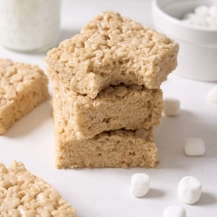 a three quarter view photo of three rice krispie treats stacked on top of each other with a bite taken out of the top one