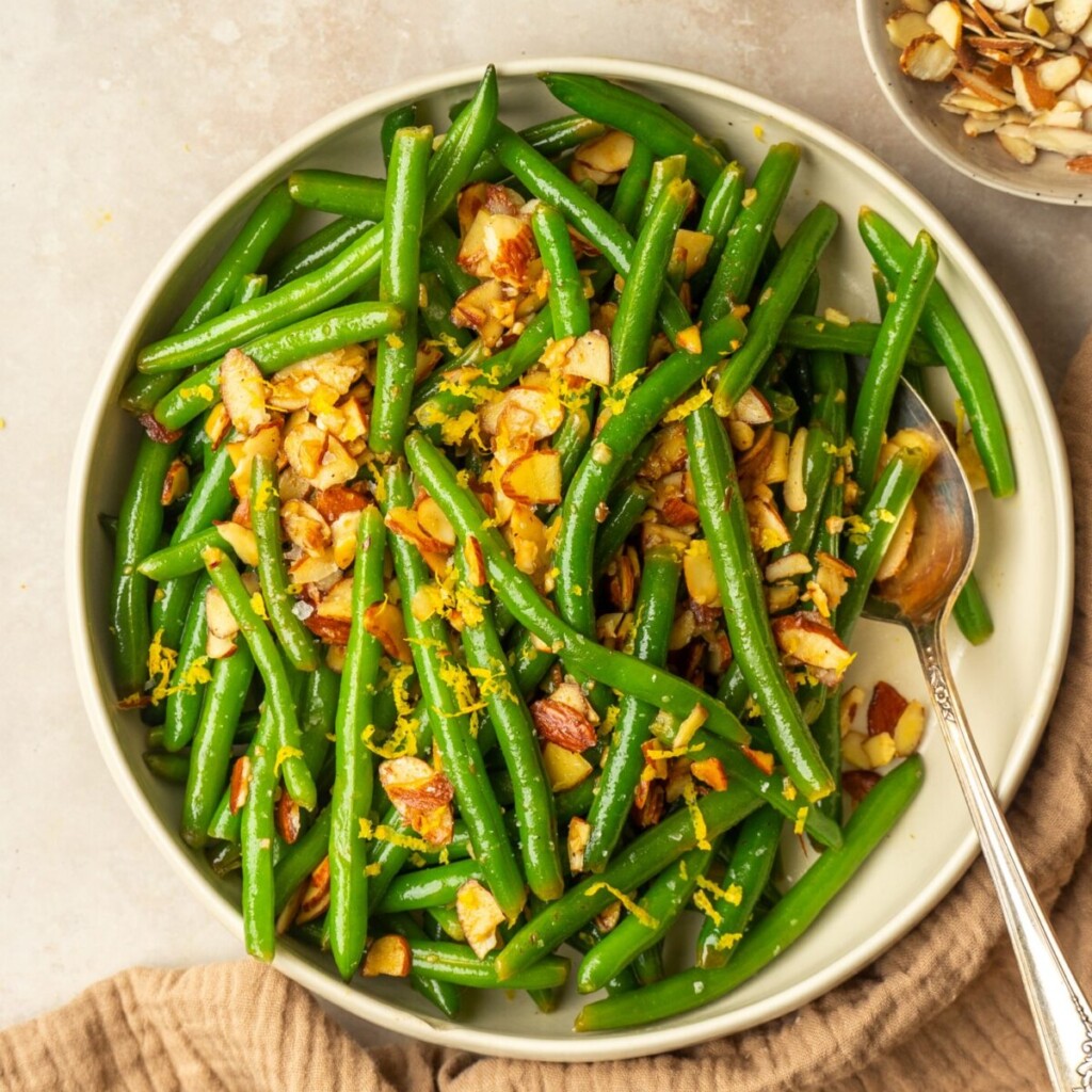 an above view image of green beans almondine in a bowl with a spoon in it