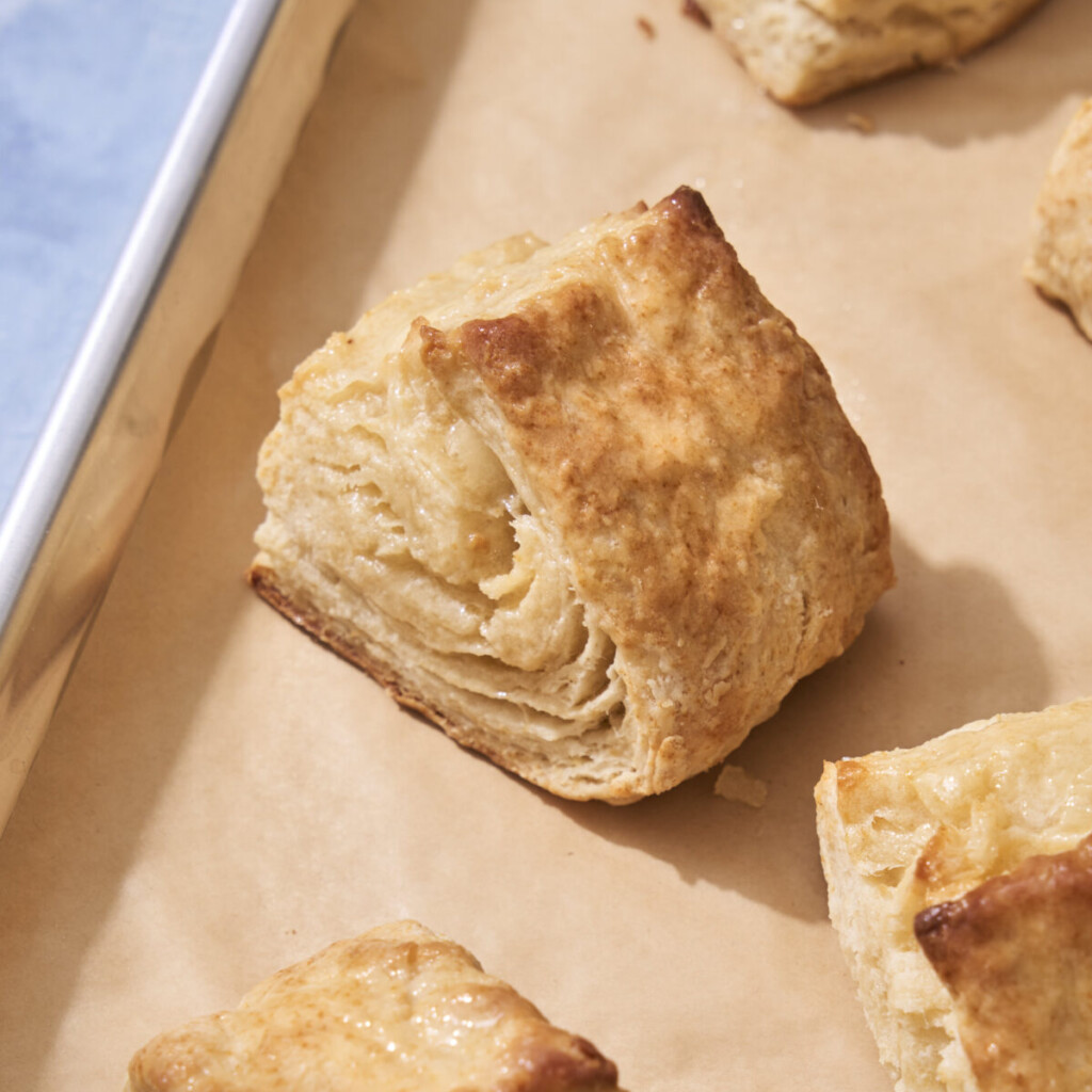 a close up photo of a honey butter biscuit on a sheet tray lined with parchment paper