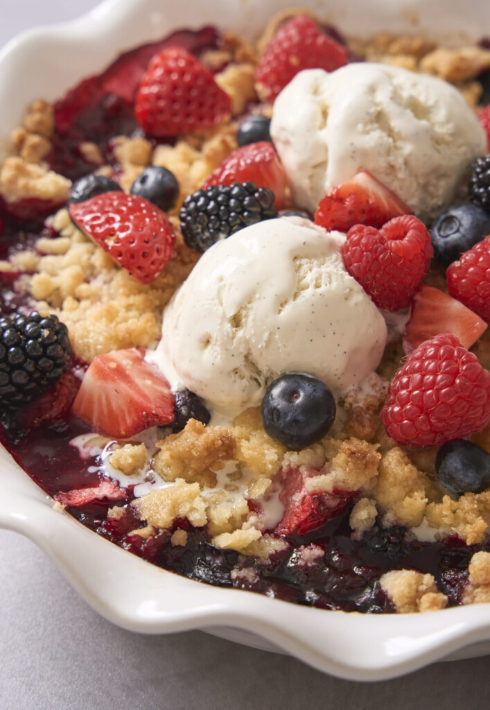 a close up image of berry cobbler with ice cream on top
