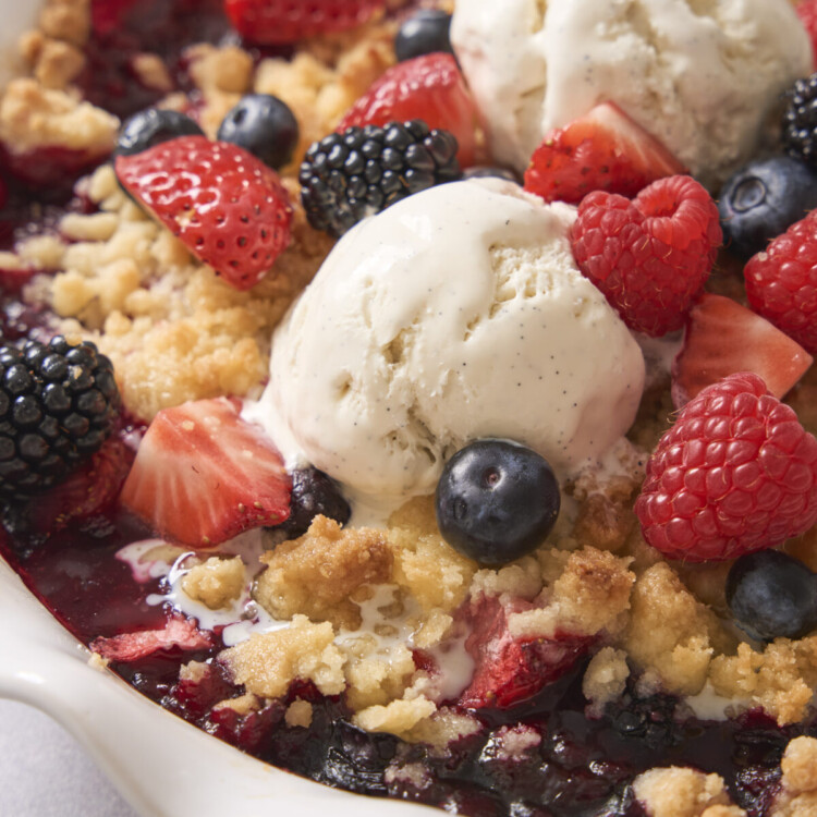 a close up image of berry cobbler with ice cream on top