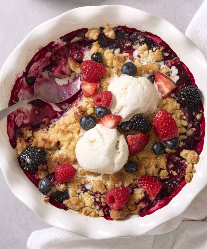 an above view image of berry cobbler in a white dish with ice cream on top