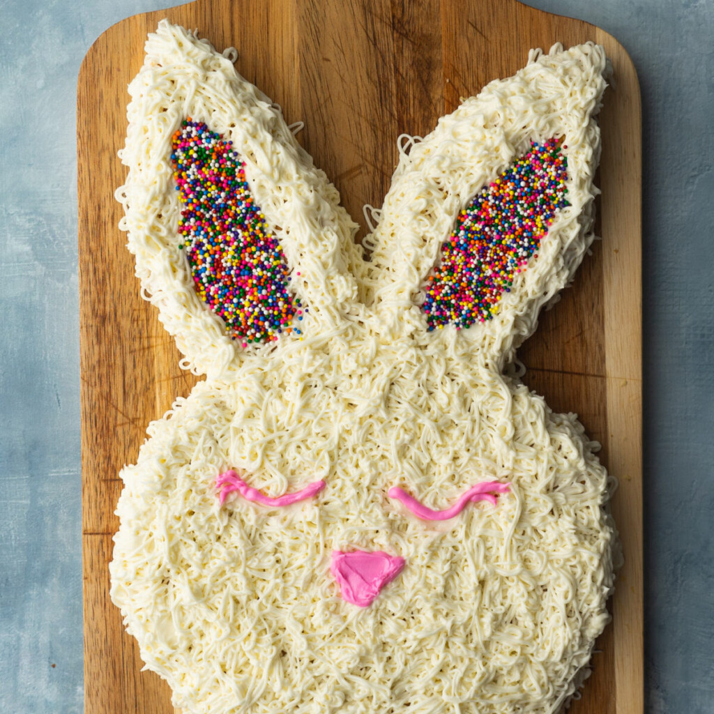 an above view image of easter bunny cake on a wooden cutting board
