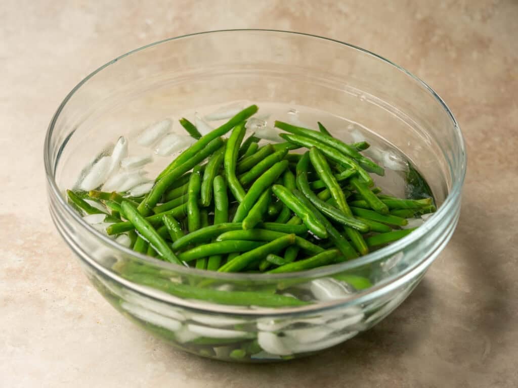 green beans in an ice bath in a glass bowl