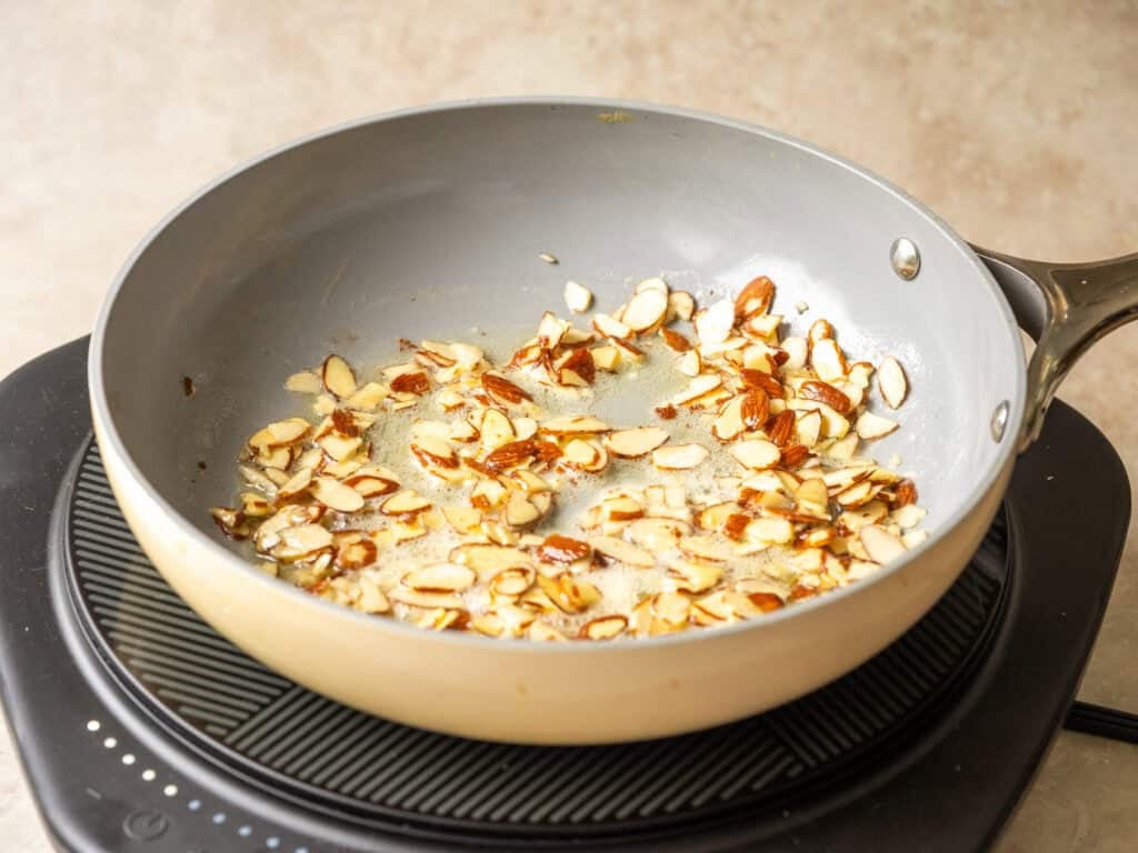 sliced almonds sauteing in a nonstick pan