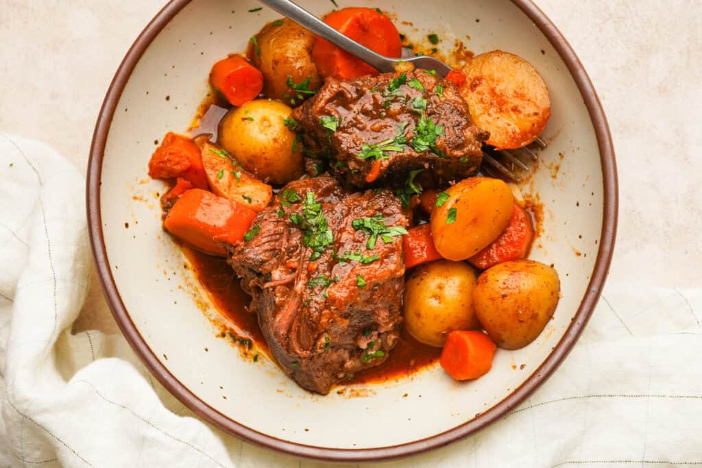 an above view photo of slow cooker short ribs with potatoes and carrots in a bowl