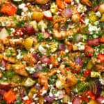 an above view photo of greek sheet pan chicken and veggies on a sheet pan