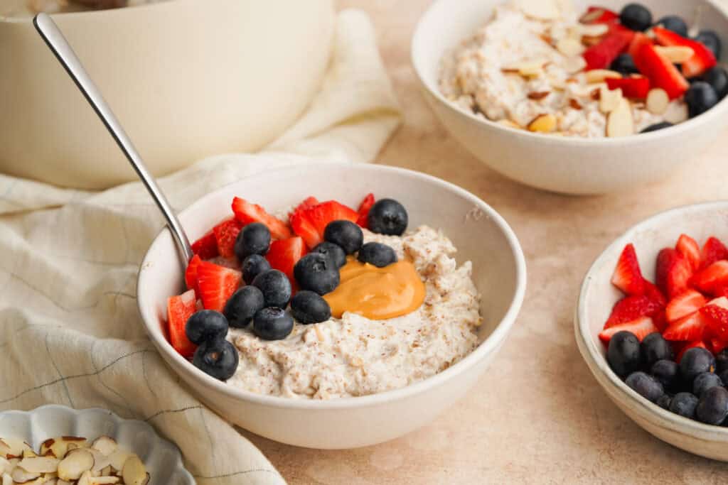 a three quarter view photo of a bowl of protein oatmeal with berries and peanut butter on top