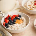 a three quarter view photo of a bowl of protein oatmeal with berries and peanut butter on top