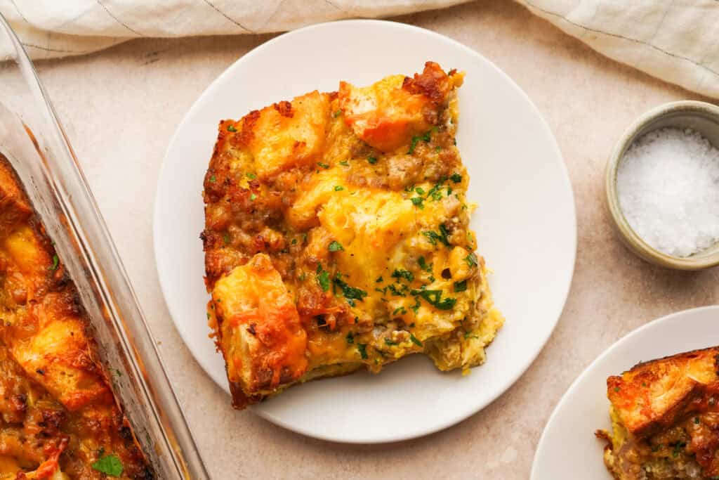 A serving plate with a slice of sausage strata breakfast casserole on it