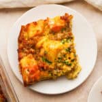 A serving plate with a slice of sausage strata breakfast casserole on it