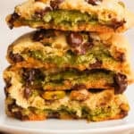 Side view of pistachio cookies broken in half stacked on top of each other with the gooey pistachio filling showing.