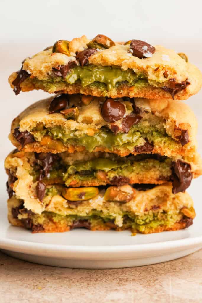 Side view of pistachio cookies broken in half stacked on top of each other with the gooey pistachio filling showing.