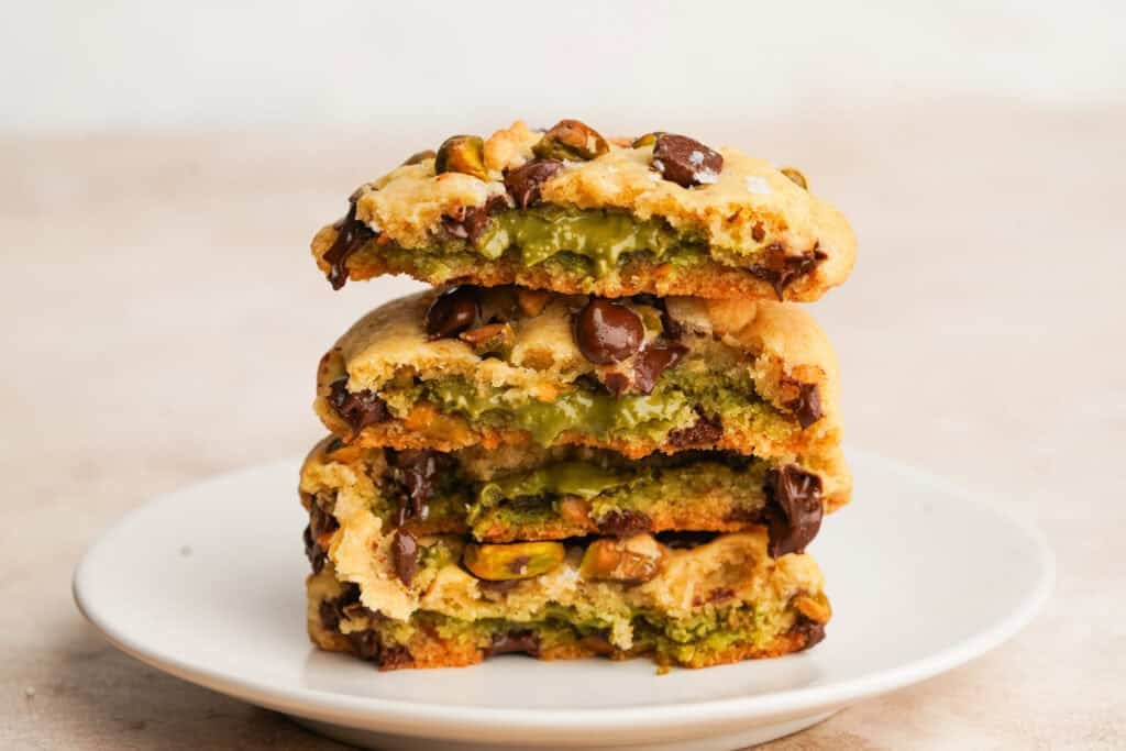 Side view of pistachio cookies broken in half stacked on top of each other with the gooey pistachio filling showing.