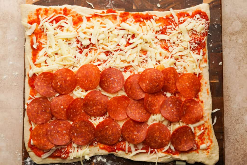 pepperoni layered on top of sauce and cheese on pizza dough