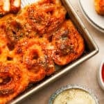 an above view photo of pizza pinwheels in a pan with small bowls of sauce and parmesan next to them