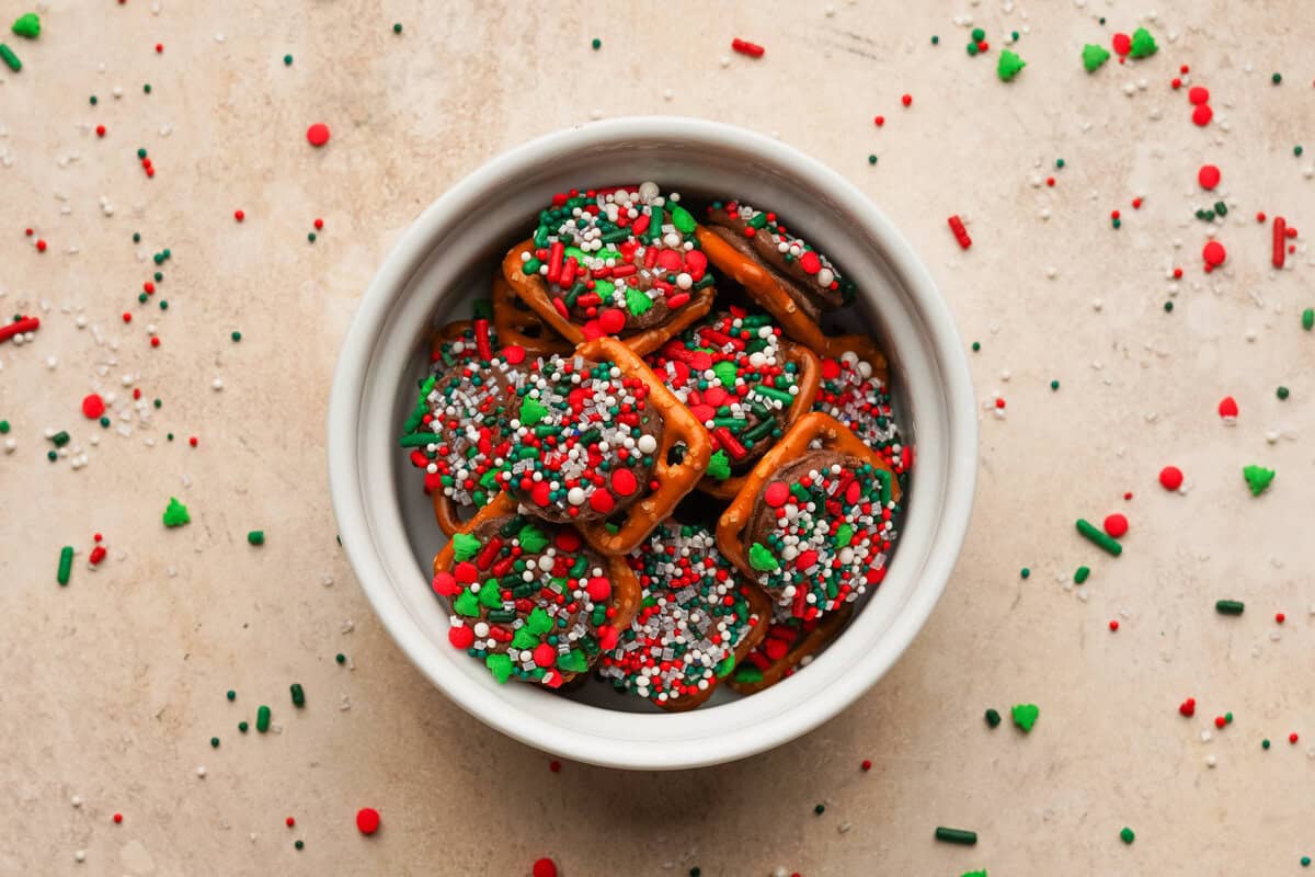 Rolo pretzel bites in a small ceramic cup with sprinkles all around the bag