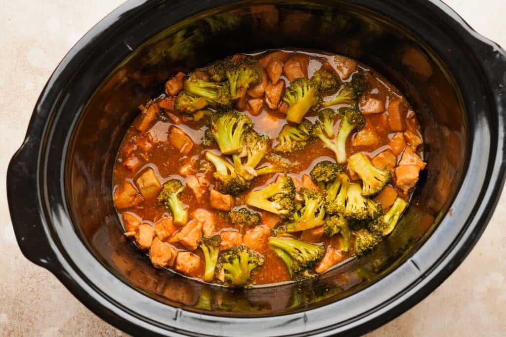an above view photo of orange chicken and broccoli in a crockpot