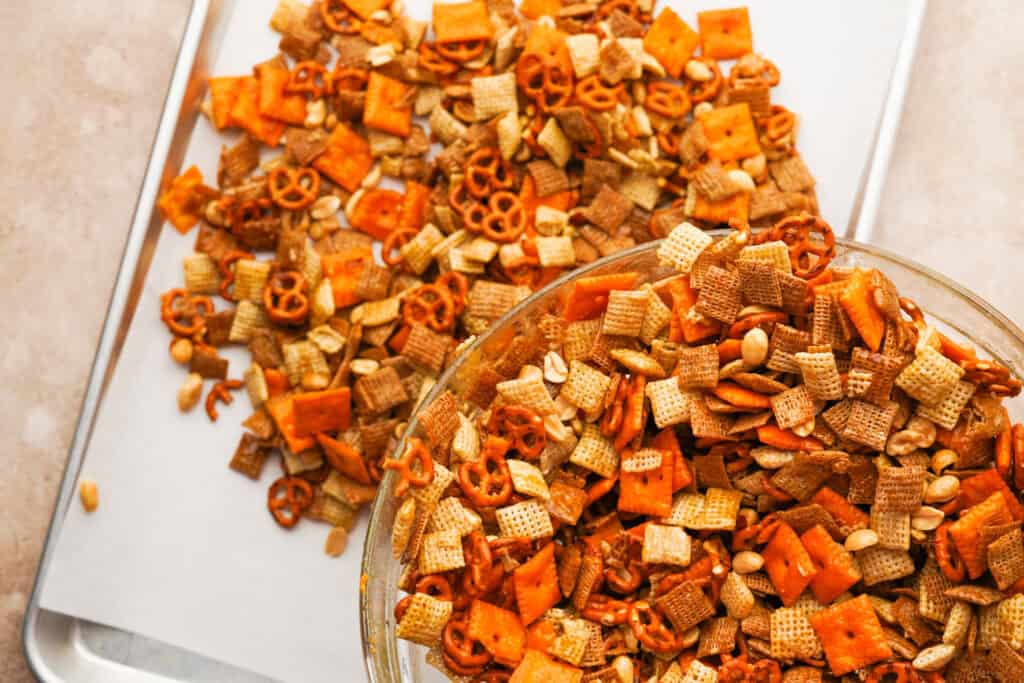 mixed ingredients pouring out of the glass bowl onto a baking sheet lined with parchment paper