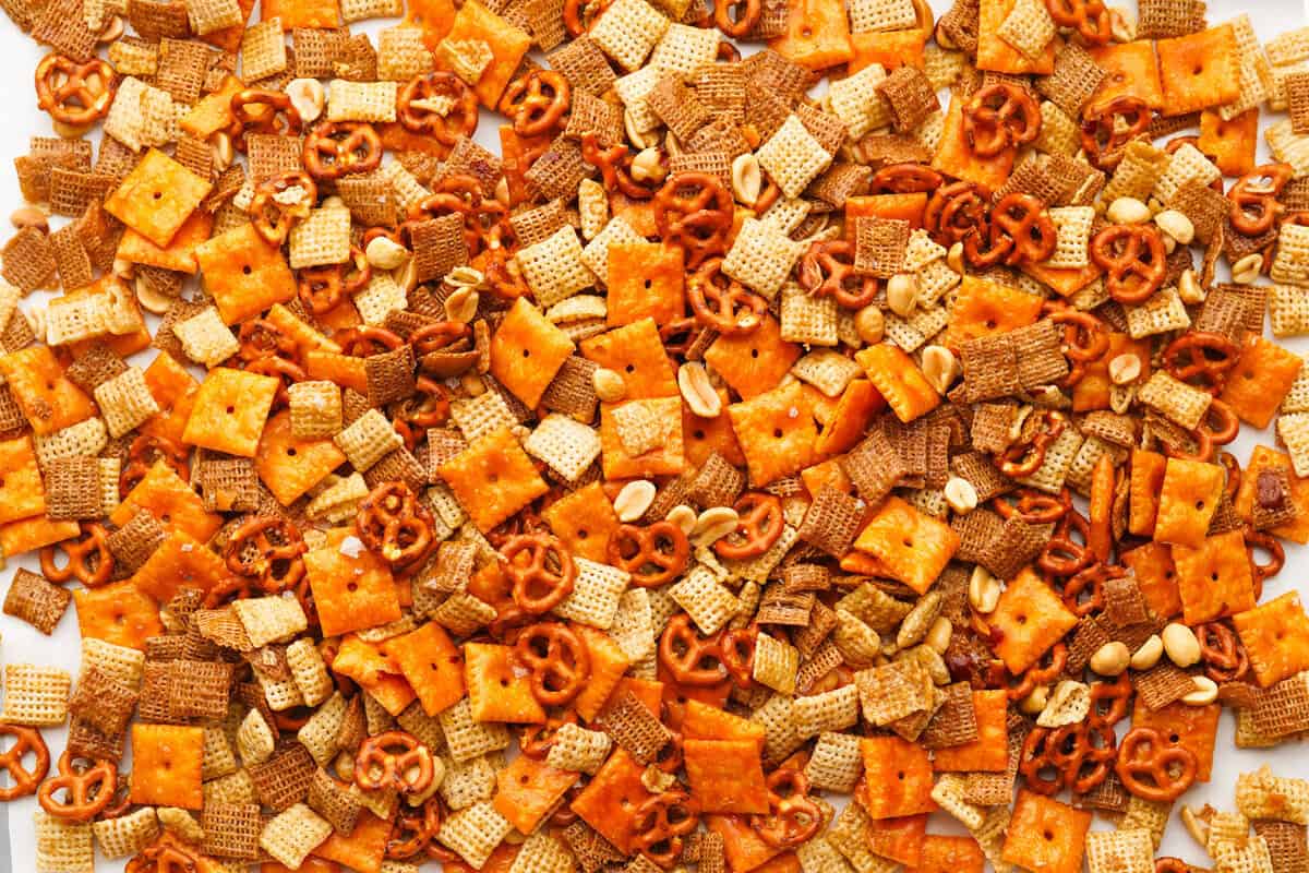 close up view of the cooked sweet and salty chex mix. chex cereal, cheez its, pretzels and peanuts are coated in a sweet and buttery coating