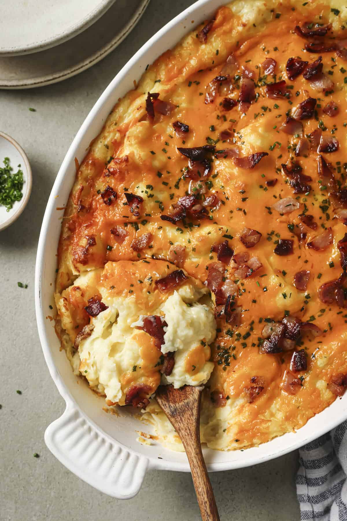 overhead shot of a cheesy twice baked potato casserole in a ceramic dish