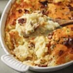 overhead shot of a cheesy twice baked potato casserole being dug into with a wooden spoon