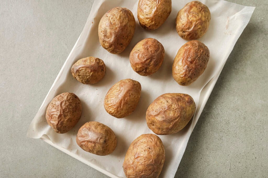 a baking sheet lined with parchment paper and baked potatoes 
