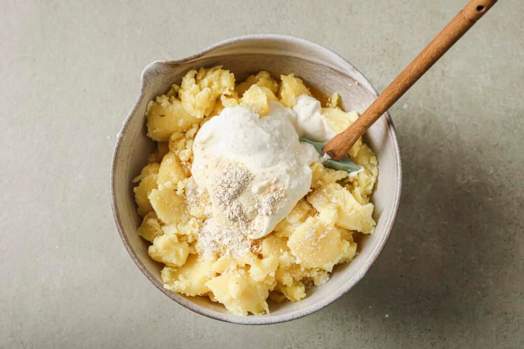 a ceramic bowl with baked potato, sour cream, and seasonings 