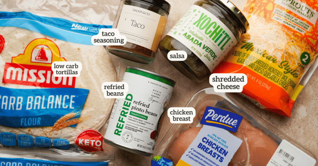 overhead shot of the ingredients used to make freezer friendly chicken burritos including tortillas, a can of refried beans, taco seasoning, salsa, shredded cheese, and chicken breast