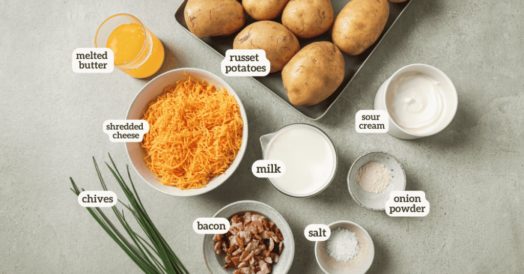 overhead shot of russet potatoes, melted butter, shredded cheese, milk, sour cream, onion powder, salt, bacon, and chives 