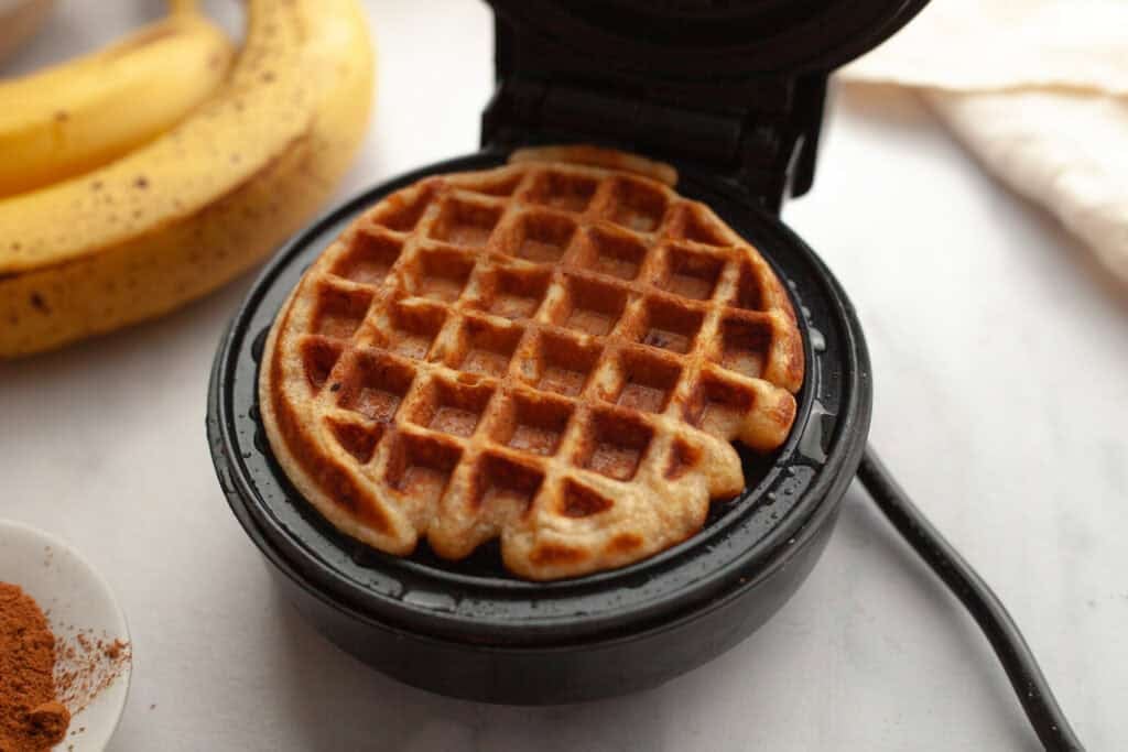 a golden brown cooked banana waffle in a mini waffle iron
