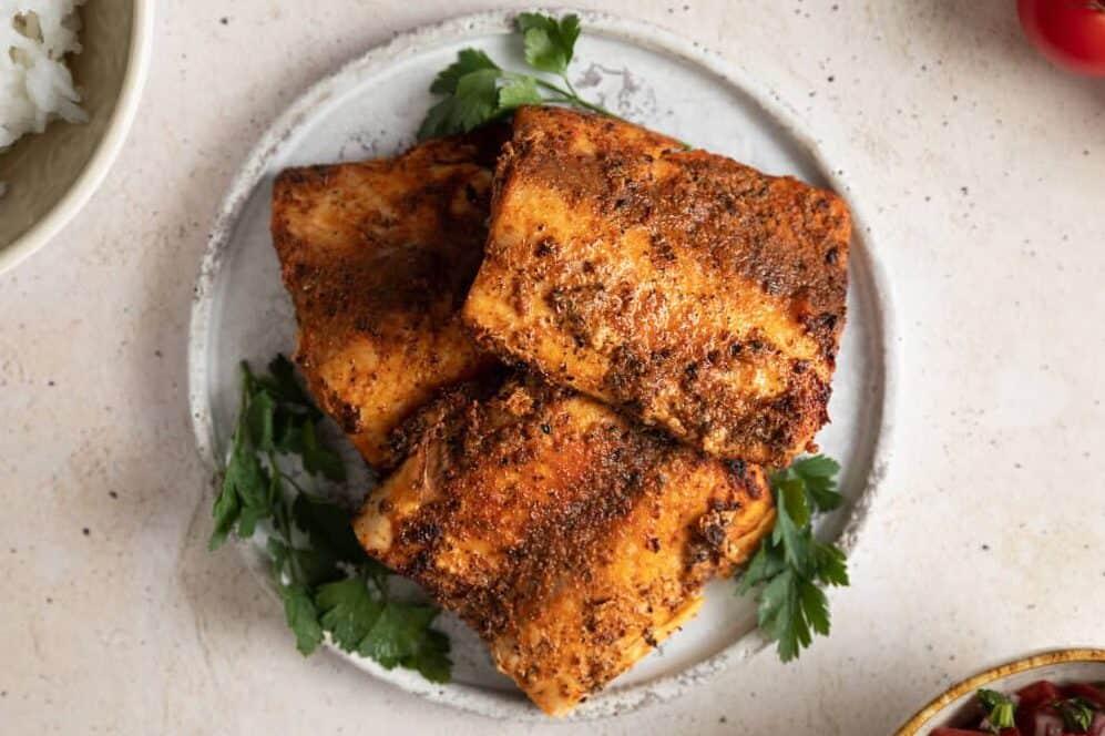 blackened mahi mahi pieces stacked on a white plate