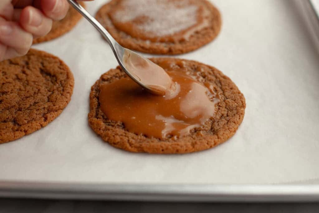 caramel topping being spread on cookie