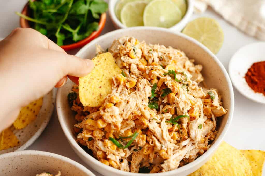 chip being dipped in mexican street corn chicken salad