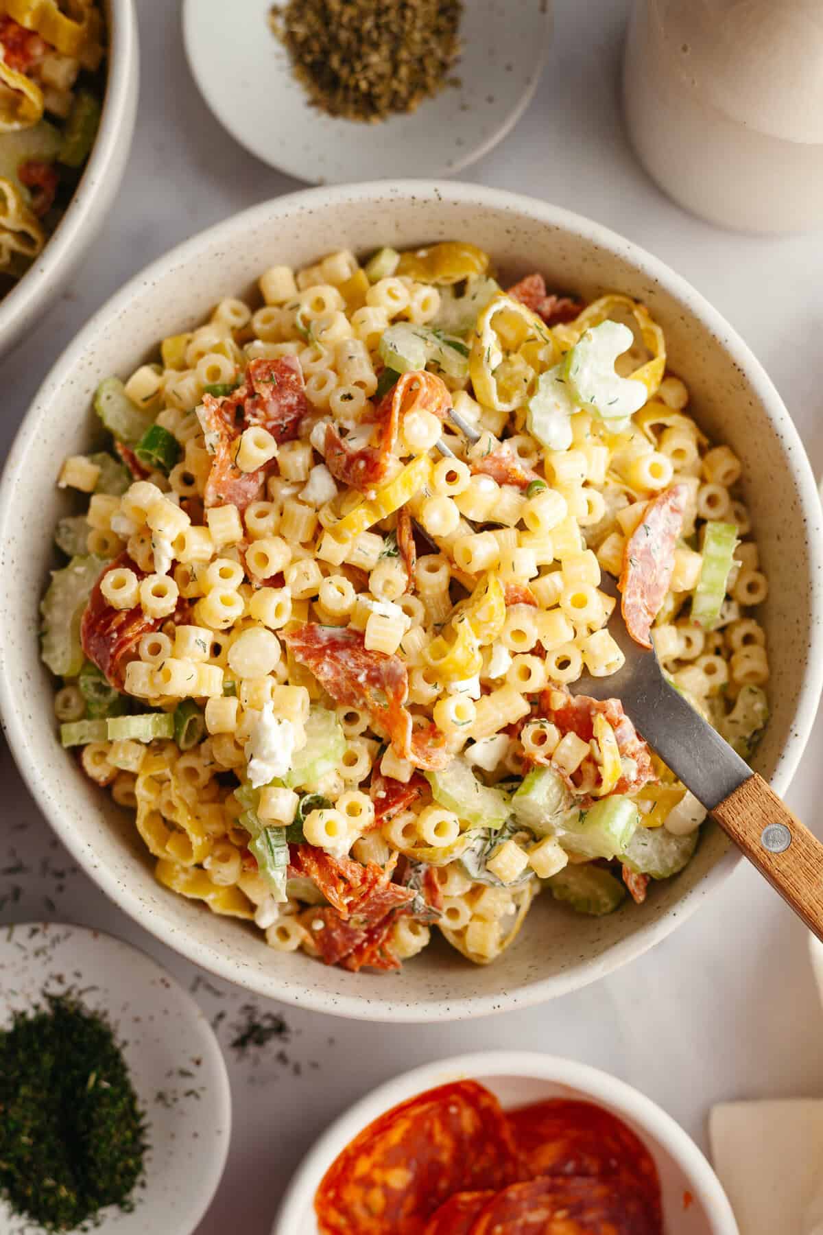 Pepperoni and pepperonicini pasta salad in a serving bowl with a serving spoon in the bowl