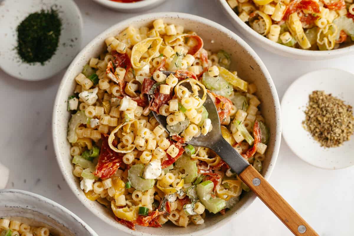 Pepperoni and pepperonicini pasta salad in a serving bowl with a serving spoon in the bowl