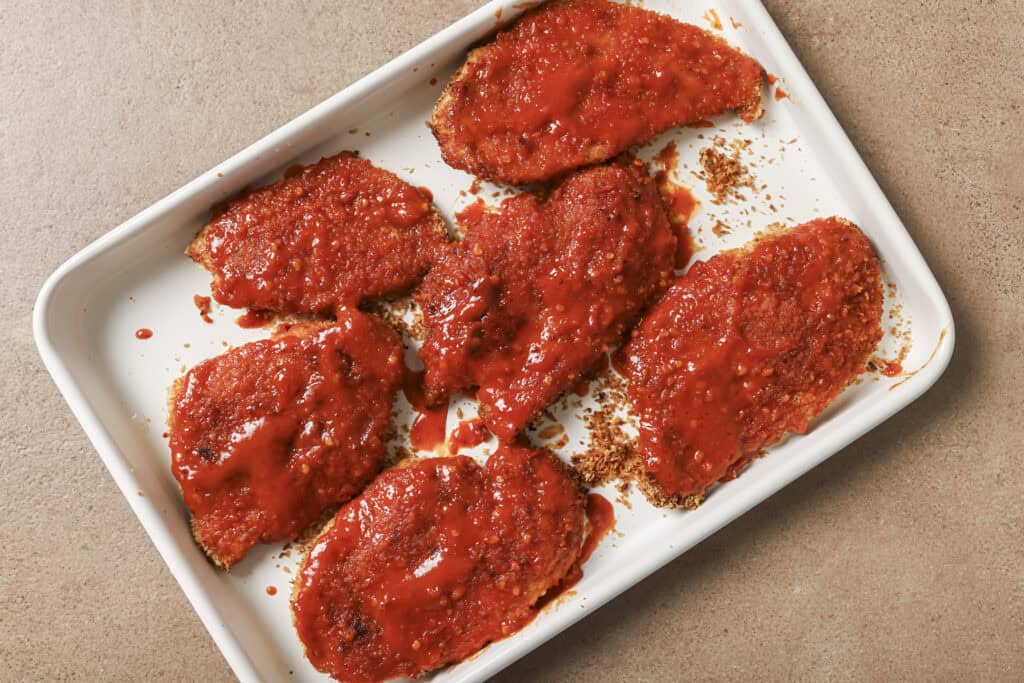 hot sauce and butter mixture on top of chicken cutlets