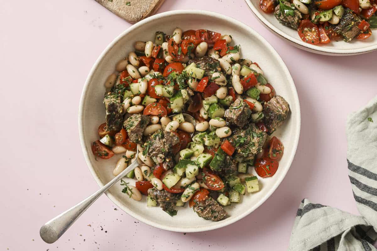 Chimichurri steak salad in a serving bowl with a serving spoon in the bowl
