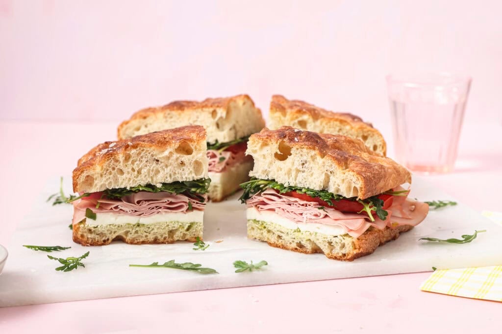 A summer focaccia sandwich cut into slices on a marble serving platter