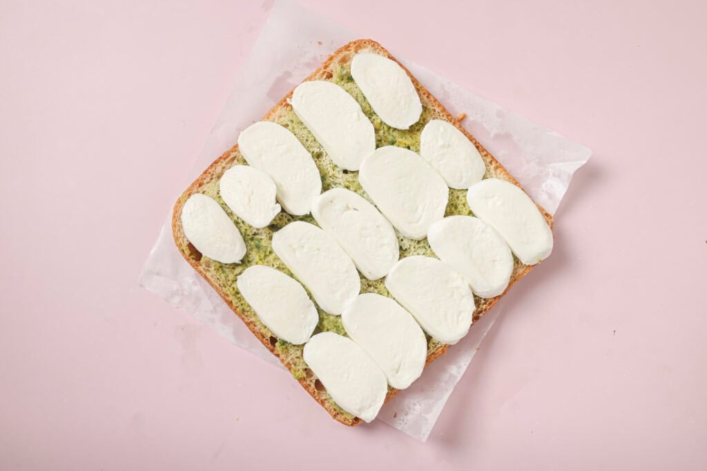 A loaf of focaccia with olive spread on the bottom and mozzarella slices on top