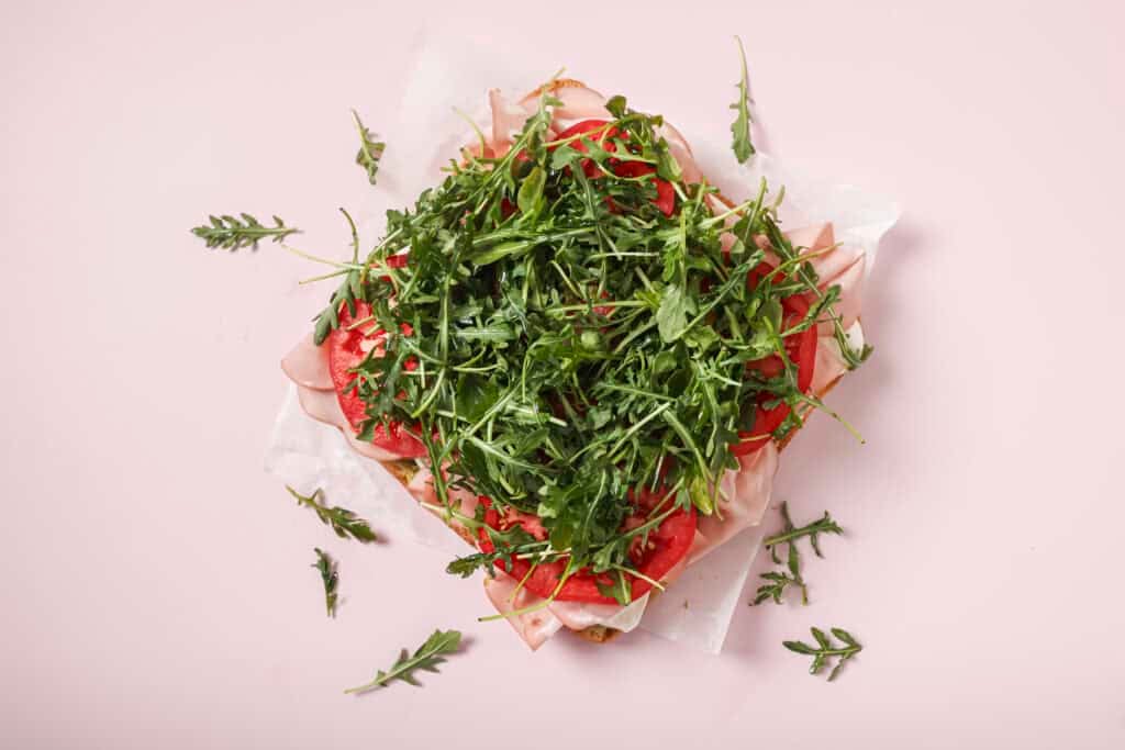 Focaccia sandwich with mozzarella, mortadella, tomato slices and arugula on top