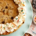 a layered cookie cake with icing on a plate, sprinkles in the background