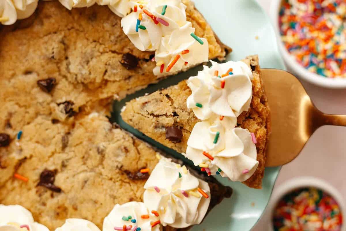 Layered cookie cake with a slice up out on a cake stand with a serving utensil pulling out the slice