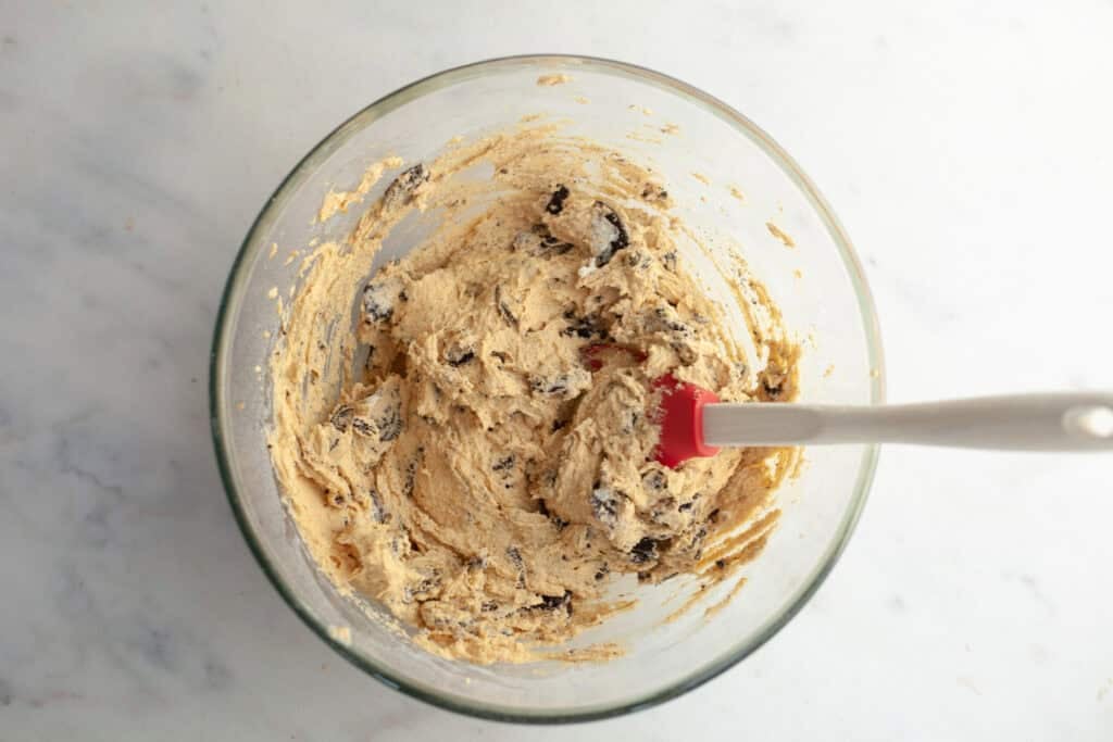 peanut butter oreo cookie ingredient batter in a bowl with oreo pieces now mixed in